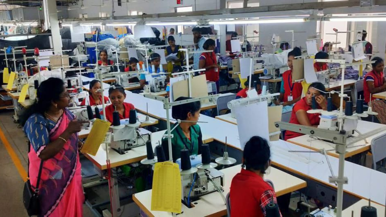 Crowded Indian factory with garment workers behind sewing machines